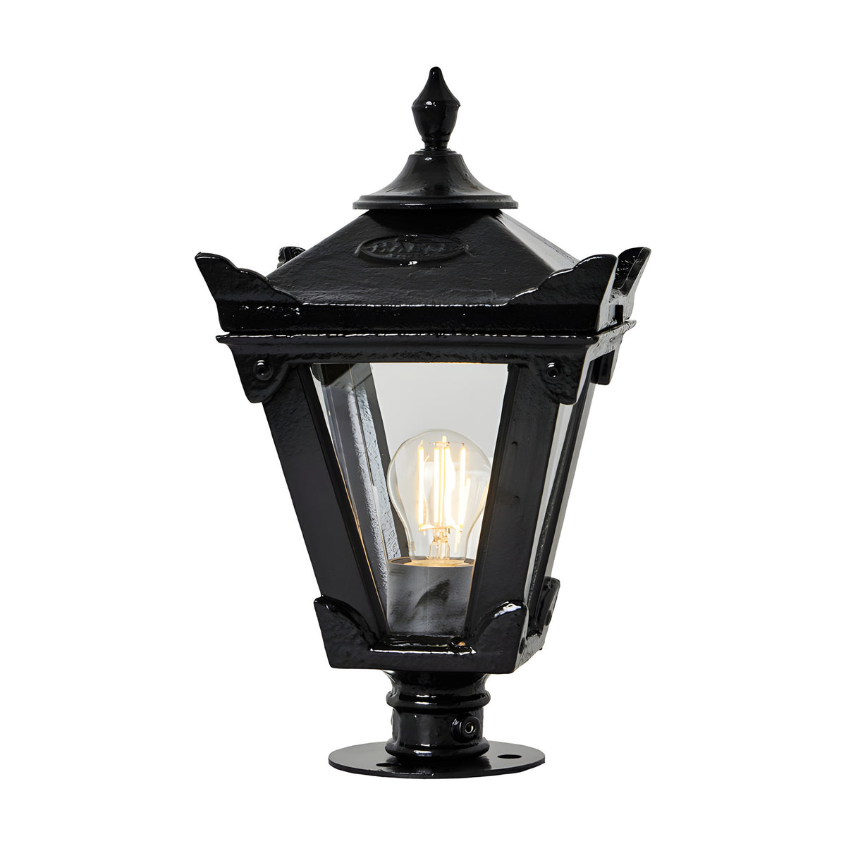 Small Victorian cast iron pillar light in black with tapered four-sided glass head, stepped crown finial and pier-cap base, shown lit against a plain white background.