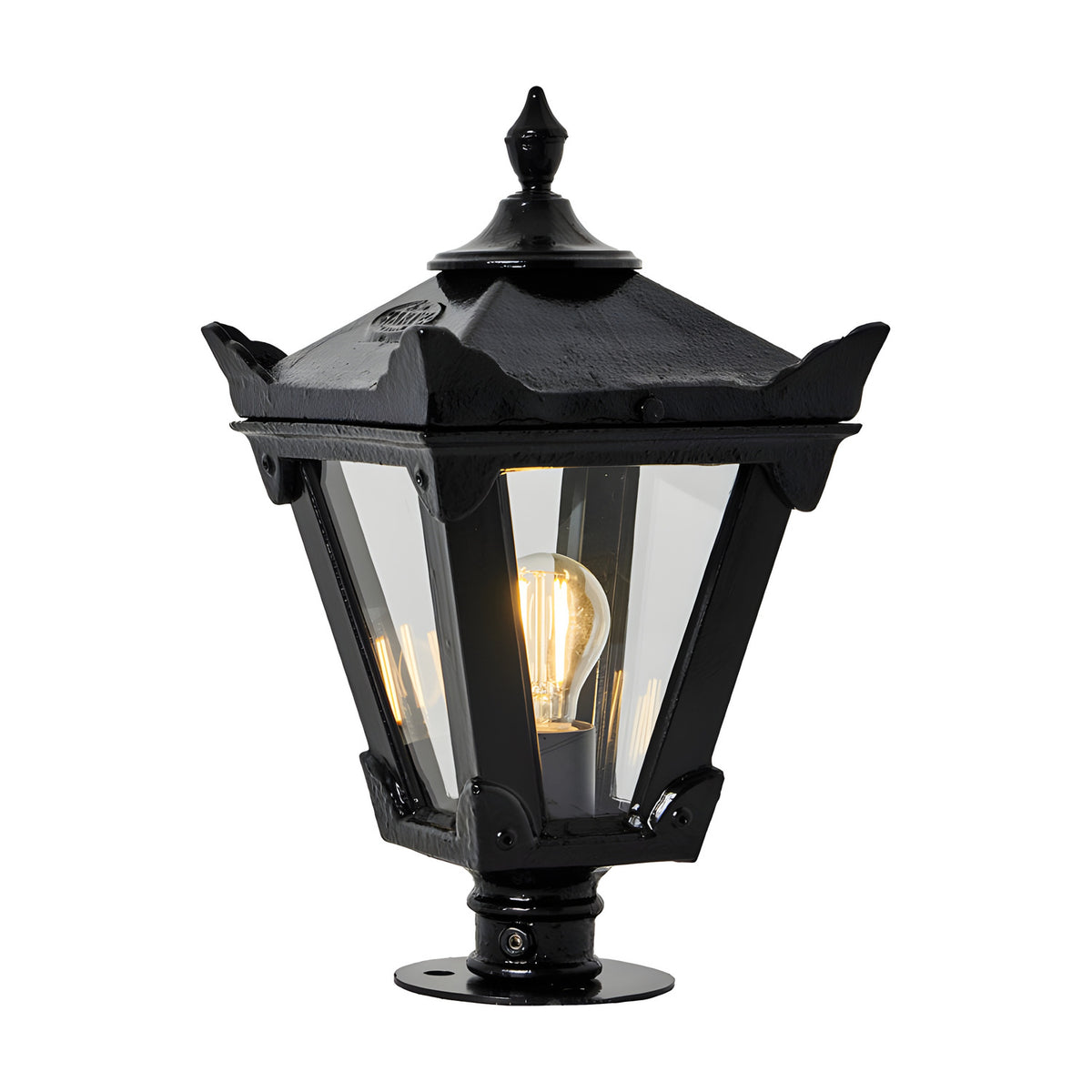 Small Victorian cast iron pillar light in black with tapered four-sided glass panels, stepped crown, corner tips and cast finial, lit bulb visible, on plain white background.