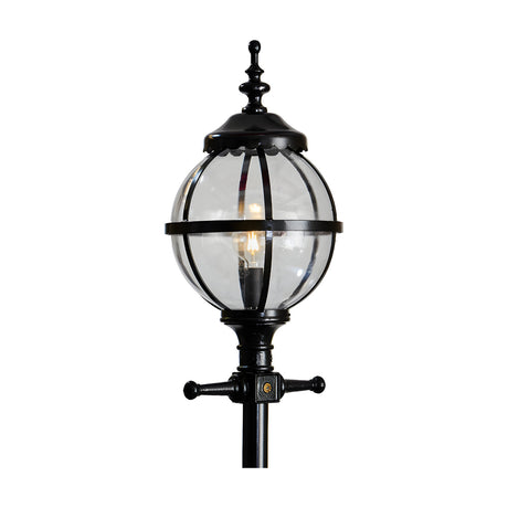 Victorian Cast Iron Globe Lamp Post in black, showing a clear glass globe shade in a banded cage cap on a decorative post, lit bulb visible, plain white background.