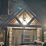 Large Victorian globe hanging lantern in black iron with banded cage, suspended on a chain from a stone-clad gable porch above a wooden entrance door.