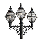 Victorian-style triple-headed lamp post in black cast iron, featuring three globe lanterns in banded cages with ornate finials and scrolled brackets, shown against a plain white background.