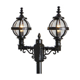 Victorian double-headed lamp post in black cast iron with two globe lanterns in banded cages, decorative scrollwork brackets and finials, shown against a plain white background.