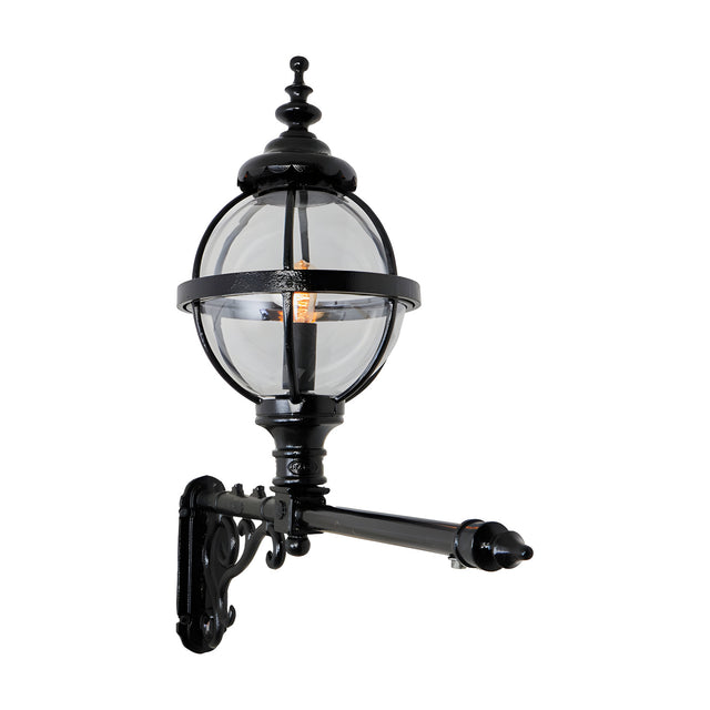 Victorian cast iron globe wall lantern in black, clear glass panels in a banded cage, mounted on a long decorative wall bracket against a plain white background.