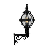 Small Victorian Globe Wall Lantern in black, cast iron banded cage globe with clear glass and lit bulb, mounted on a scroll bracket, shown on a white background.