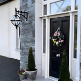 Large Victorian downturned globe wall lantern in black cast iron with clear polycarbonate glazing, mounted on a grey stone pillar beside a black front door.