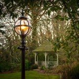 Victorian Manor cast iron globe lamp post in black, 3m column with banded cage globe, illuminated in a garden setting near a gazebo.