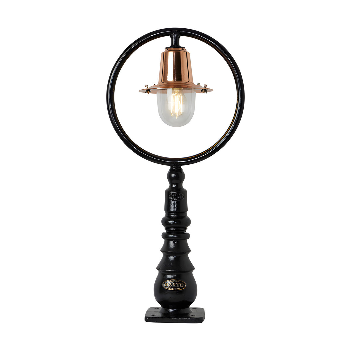 Small railway style cast iron pedestal post light with a black circular hoop frame, copper spun shade, and clear glass dome on a black turned base, plain white background.