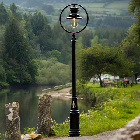 Railway Style Cast Iron Lamp Post 3.65m in black, single lantern head with hoop and glazed dome, shown beside a riverside path in a green outdoor setting.