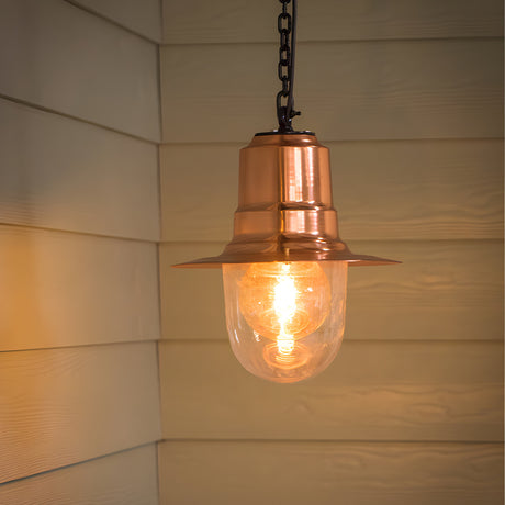 Medium Railway Style hanging lantern with a copper spun shade and clear glass dome, hung from a black chain against a light wooden panelled wall.
