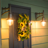 Small railway style wall lanterns on cast arms in black, mounted either side of a front door, each with a spun shade over a clear glass dome, illuminated at dusk.