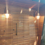 Two Small Vintage Wall Lanterns on gooseneck brackets with copper teardrop shades, mounted on a slatted wood wall either side of a black door handle.