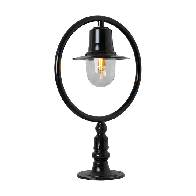 Large black cast iron railway-style pillar light with circular hoop frame, spun shade, and clear glass dome over a single bulb, mounted on a pier cap base.