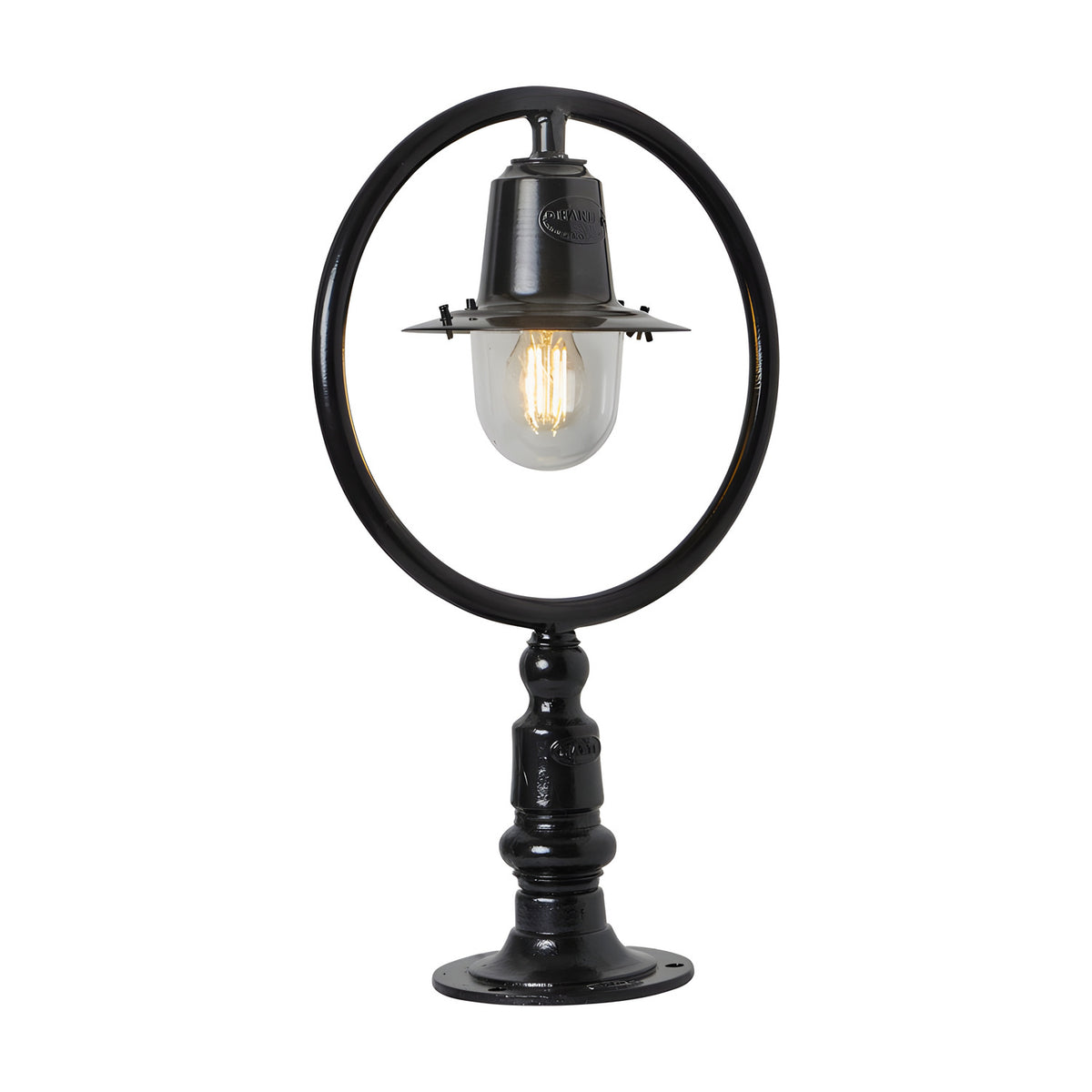Small Railway Style Cast Iron Pillar Light in black, with a circular hoop frame over a spun shade and clear glass dome, mounted on a flat pier base, shown on a plain white background.