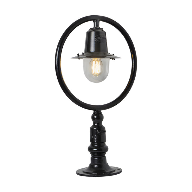 Small Railway Style Cast Iron Pillar Light in black, with a circular hoop frame over a spun shade and clear glass dome, mounted on a flat pier base, shown on a plain white background.
