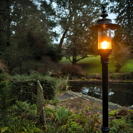Georgian cast iron lamp post in black, 2.55m tall with a lantern-style glass head and shallow crown, illuminated in a garden setting beside a pond.