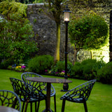 Georgian Cast Iron Lamp Post 2.21m in black, traditional single-light post with lantern head, shown illuminated on a lawn beside a garden table and chairs.