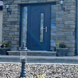 Small Georgian cast iron pedestal post light in black with clear polycarbonate lantern, shown on gravel outside a stone house with a dark front door.