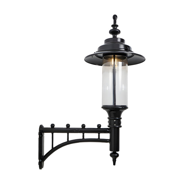 Large Georgian cast iron wall lantern in black with a decorative scroll bracket, clear cylindrical glass shade and domed crown, shown against a plain white background.