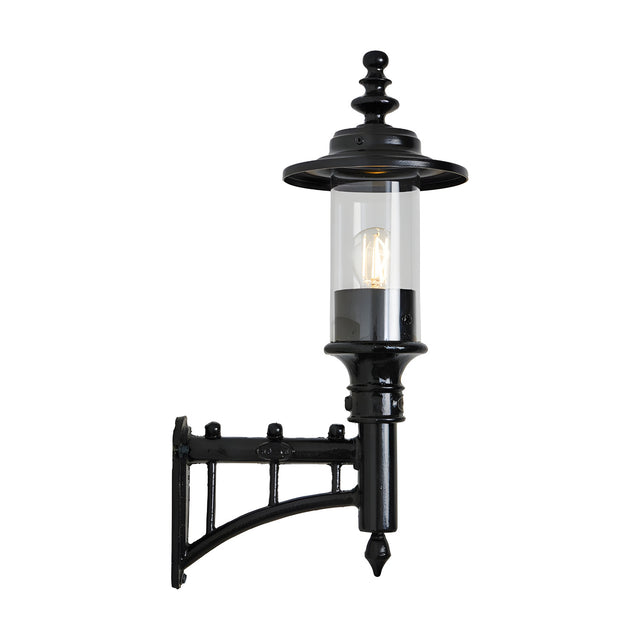 Small Georgian cast iron outdoor wall lantern in black, single-light with clear cylindrical glass shade and decorative wall bracket, shown on a plain white background.