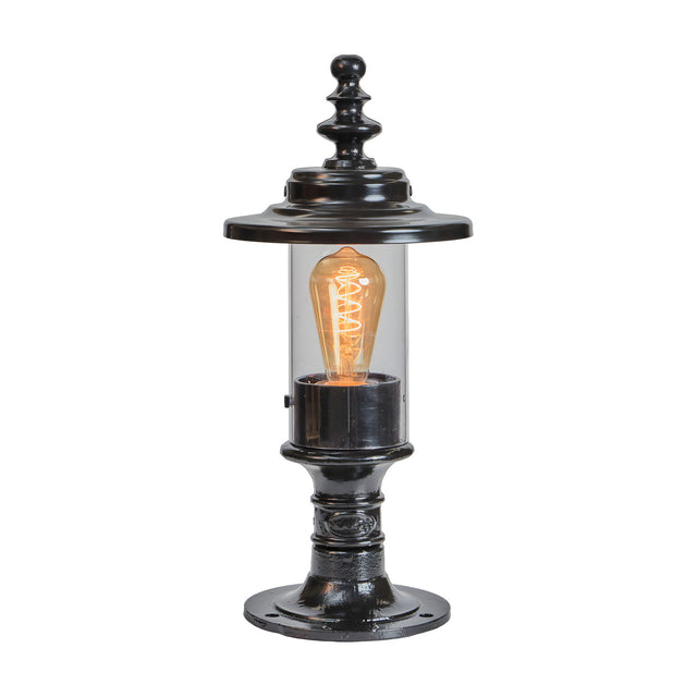 Small Georgian cast iron pillar light in black with clear cylindrical glass shade, ornate finial top, and pedestal base, shown on a plain white background.