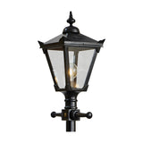 Close-up of the Victorian Manor cast iron lamp post's lantern head in black, with a pointed finial, sloped roof, clear glass panels and visible bulb, on a plain white background.