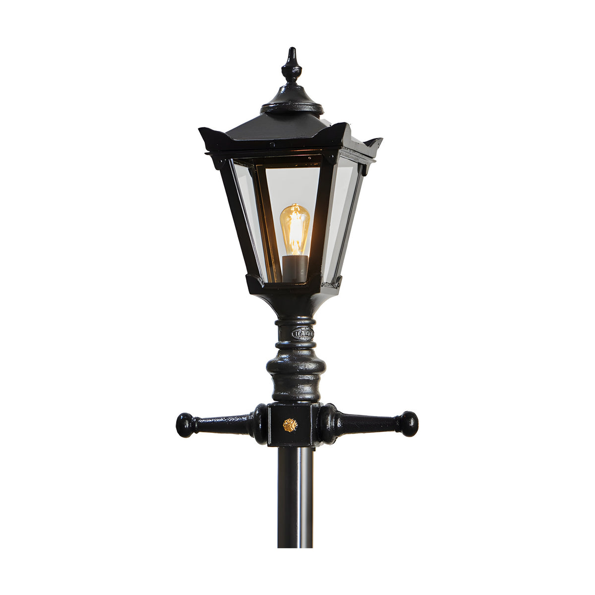 Victorian Manor cast iron lamp post in black with a hexagonal lantern head, decorative finial, cross arms and clear polycarbonate glazing around a lit E27 bulb, shown against a plain white background.