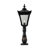 Black cast iron pedestal post light with Victorian Manor lantern design, glass panels, ornate finial, slim column, and base plate, shown on a white background.