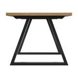 Hyde dining table end-view showing a whiskey wood-effect top on a black metal trapezoid leg frame with cross bar support, set against a plain white background.