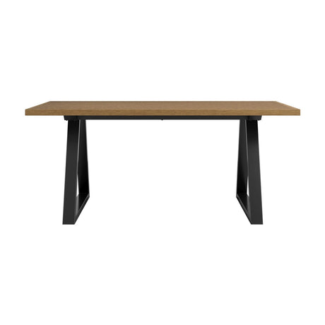 Hyde dining table with a whiskey-toned wood-effect top and angled black metal trestle legs, shown on a plain white background.