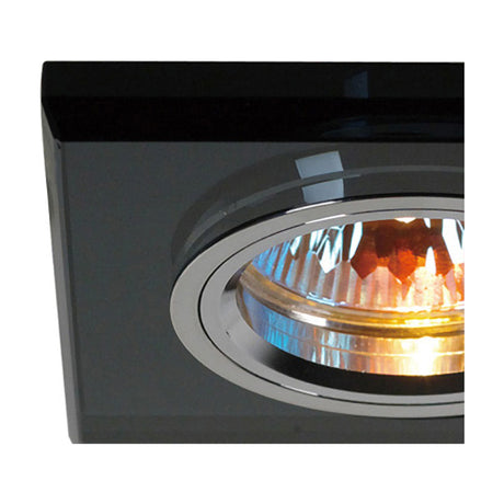 Close-up of a square black crystal downlight rim with chrome inner trim, 90mm face and 62mm cut-out, showing the illuminated bulb inside.