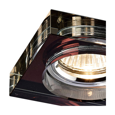 Close-up of a square crystal downlight rim in deep purple with chrome trim, 90mm face and 62mm cut-out, shown against a white background with the halogen bulb visible.