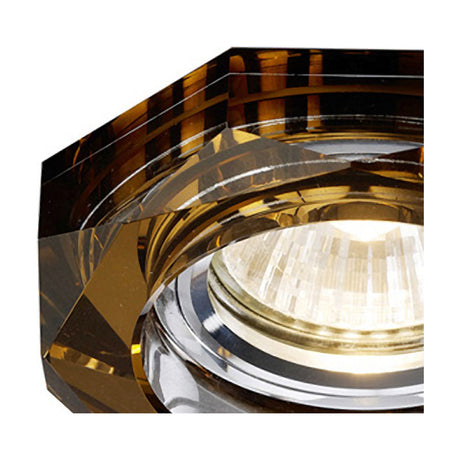 Close-up of a bronze crystal downlight rim with an octagonal, deep-cut faceted profile, 90mm diameter for a 62mm cut-out, shown with a lit bulb inset.