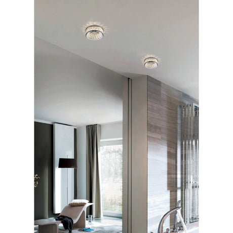 Dante Downlight 60mm Cut-Out in polished chrome, shown recessed into a white ceiling with crystal bead detailing, lighting a modern living space with wooden panelling and neutral décor.