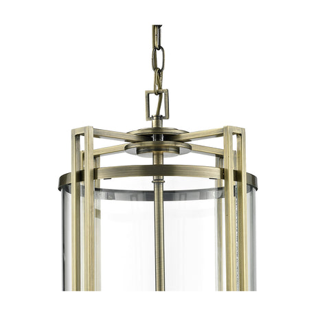 Close-up of the Eaton 3 Light E14 Pendant Light in antique brass, showing the geometric frame, clear cylindrical glass shade, and chain suspension against a white background.