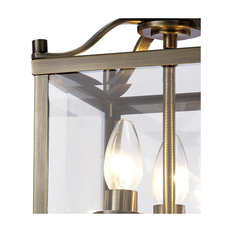 Close-up of the Aston 3 Light Semi Flush Ceiling Light in antique brass, showing a squared frame, clear glass panel, and lit candle bulb detail.
