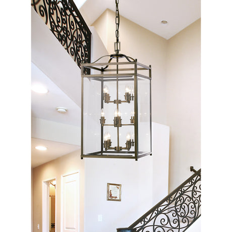 Aston 12 Light E14 Pendant Light in antique brass with a square glass-panelled frame and exposed candle bulbs, hung from a chain above a staircase in a hallway.