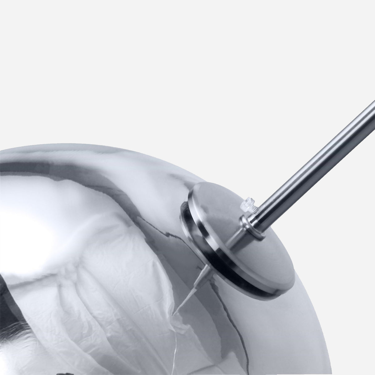 A close-up view showcasing the metallic, mirror-like Grand Ball Glass Pendant in silver, measuring 25 cm, with a precision instrument attached to its side. The scene is enhanced by LED compatible lighting against a plain light gray background, highlighting its modern aesthetic.