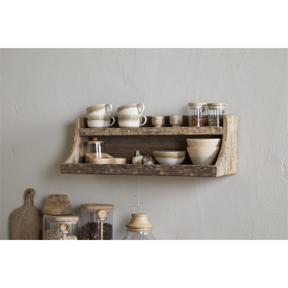 Ibo Reclaimed Wood Wall Shelf in natural finish, two-tier design with curved side brackets, mounted on a kitchen wall holding mugs, jars, bowls and garlic.