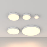Five Zon LED Downlight 3000K 12W lamps, resembling circular ceiling lights, are symmetrically installed on a white ceiling. These minimalistic lights emit a soft, warm glow, with larger ones positioned at the bottom and smaller ones at the top.