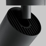 Close-up of the Focus Zoom LED Single Surface-Mounted Spotlight 12W 4000K in black, showcasing a modern cylindrical design with an open top and vertical grooves against a plain gray background, featuring LED spotlight technology for enhanced ambiance.