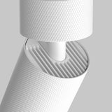 Close-up of a modern white cylindrical Artisan Single Spotlight with a ribbed interior and smooth joint. The geometric pattern offers premium lighting in sleek, minimalist interiors against a plain gray background.