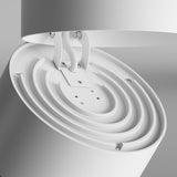 The Yin LED Single Spotlight 15W 3000K - White features a modern, minimalistic design with a circular, layered look. It offers excellent color rendering with a CRI of 90. Its smooth surface is suspended by wires for a sleek contemporary appearance against a neutral background.