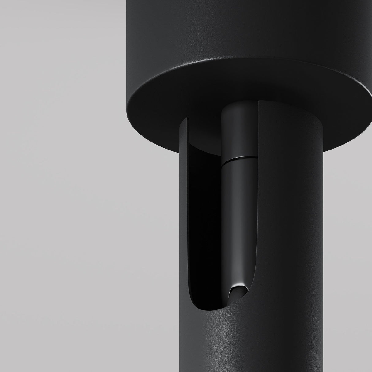 Close-up of the Focus T LED Long Single Spotlight in black, showcasing its sleek, modern cylindrical form with a smooth matte finish. The spotlight features a recessed open section revealing internal components against a neutral gray background, embodying minimalistic and industrial design ideal for modern interiors.