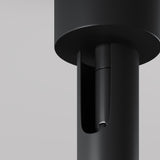 Close-up of the Focus T LED Long Single Spotlight in black, showcasing its sleek, modern cylindrical form with a smooth matte finish. The spotlight features a recessed open section revealing internal components against a neutral gray background, embodying minimalistic and industrial design ideal for modern interiors.