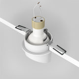 The Lipari Fixed Recessed Downlight in White & Gold combines minimalist elegance with a ceiling-mounted design, perfect for focused lighting. It includes exposed wiring and metal clips for easy installation, set against a sophisticated gray background.