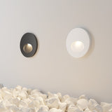 The Bil Outdoor LED Recessed Wall Light in black and white, featuring energy-efficient LED technology, creates a minimalist and serene ambiance. Mounted on a neutral wall above irregularly shaped pebbles, these lamps offer a soft glow that enhances modern aesthetics.
