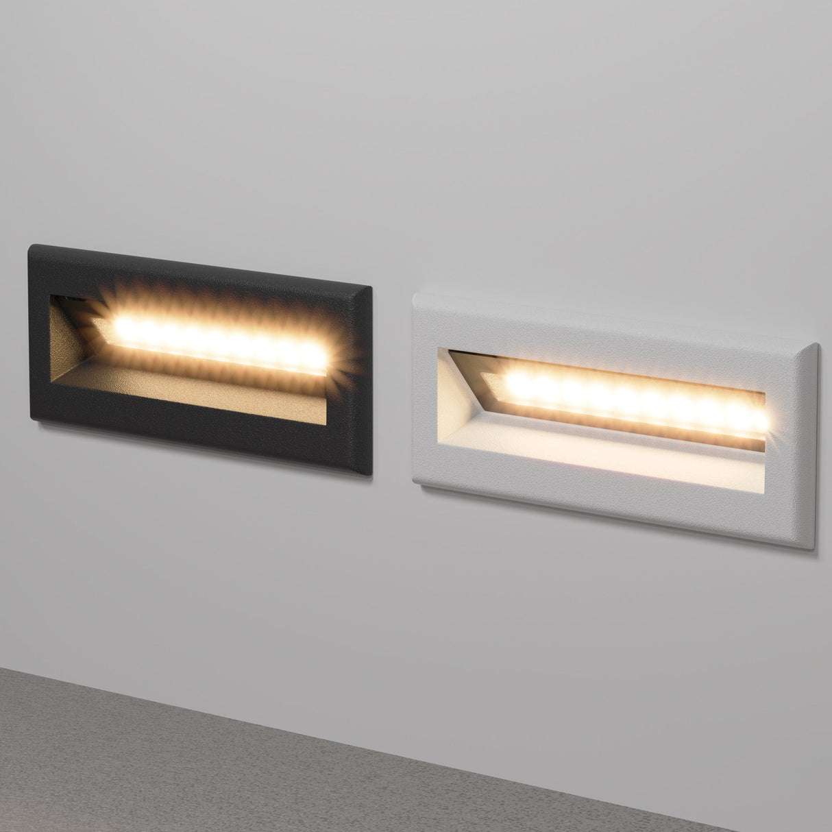 Two Bosca Outdoor LED Long Recessed Wall Lights are mounted on a white wall. The left has a black frame, the right has a white frame, both emitting a warm glow. With IP65-rated construction, they elegantly and durably illuminate any area.