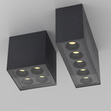 Two graphite Ares Outdoor LED Rectangular Downlights with recessed bulbs mounted on a gray ceiling feature four circular lights within a glass pane, offering a modern, minimalist look. Perfect for terraces, these fixtures bring elegance to any space.