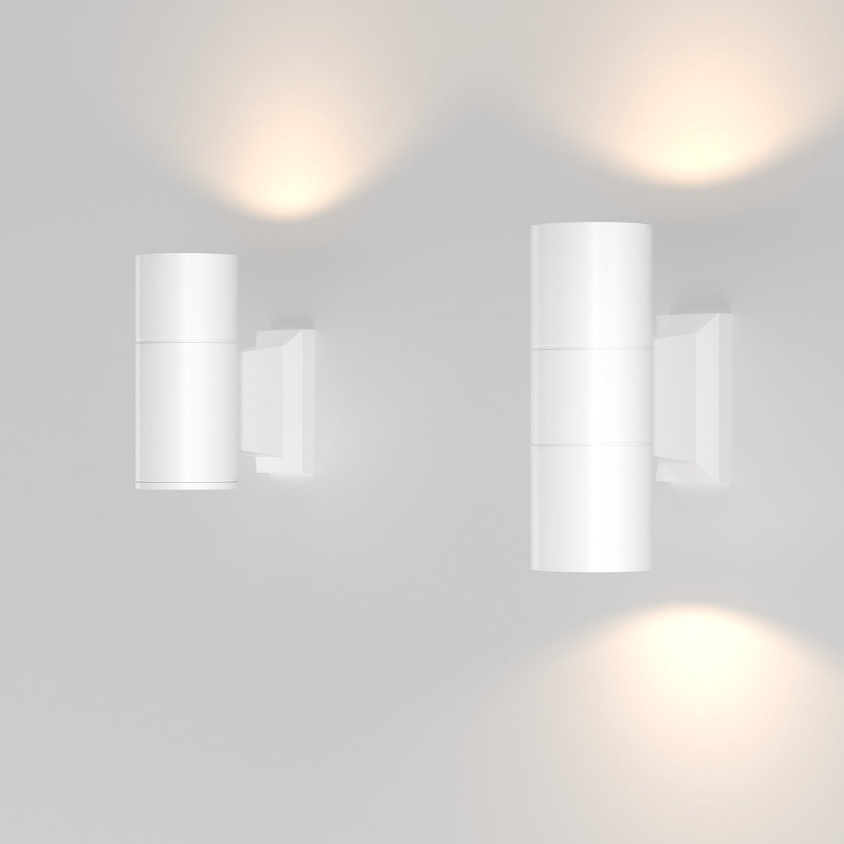 The Bowery Outdoor 2 Light Wall Light - White (O574WL-02W) fixtures, mounted on a light gray wall, emit a dual soft yellow glow both upward and downward. This creates a warm, minimalistic ambiance that greatly complements modern architecture.