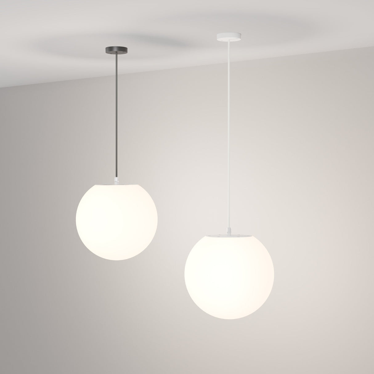 Two Erda Outdoor Pendant Lights from the Black & White collection hang from the ceiling, featuring spherical designs with one black and one white fixture. They emit a soft, white glow that gently illuminates outdoor spaces against a neutral backdrop.